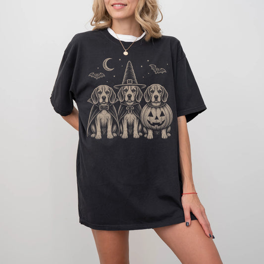 Model wearing a Black Comfort Colors® T-shirt showing three Beagle dogs dressed for Halloween beneath bats and a crescent moo
