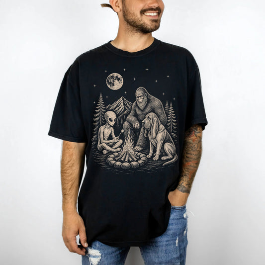 Model wearing a Black Comfort Colors® T-shirt showing Bloodhound camping with Bigfoot and an alien