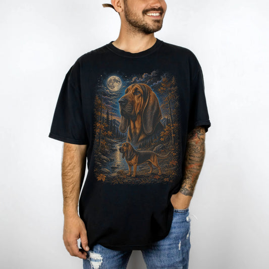 Model wearing a Black Comfort Colors® t-shirt featuring Bloodhound in a moonlit fall forest