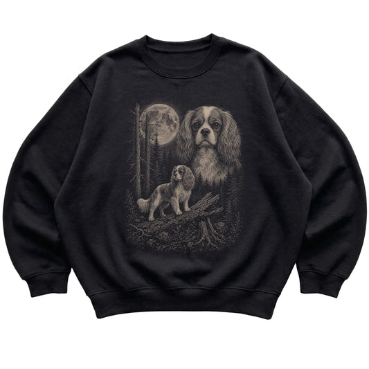 Cavalier King Charles Spaniel Moonlit Forest graphic on a black crewneck sweatshirt laid flat