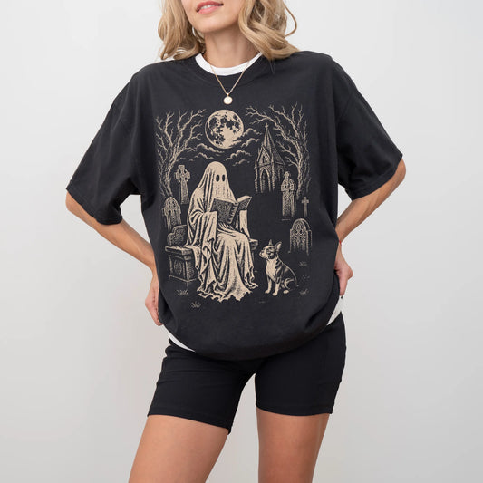Model wearing a Black Comfort Colors® T-shirt showing Boston Terrier beside a reading ghost in a moonlit graveyard