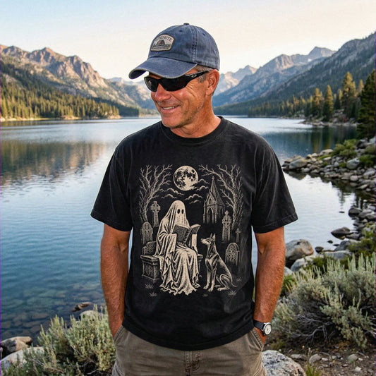 Model wearing a Black Comfort Colors® T-shirt showing Doberman beside a reading ghost in a moonlit graveyard