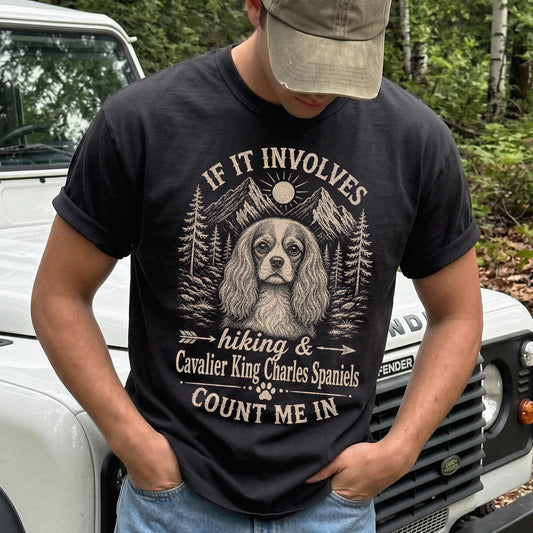 Model wearing a Black Comfort Colors® T-shirt featuring Cavalier King Charles Spaniel hiking design with mountain scenery