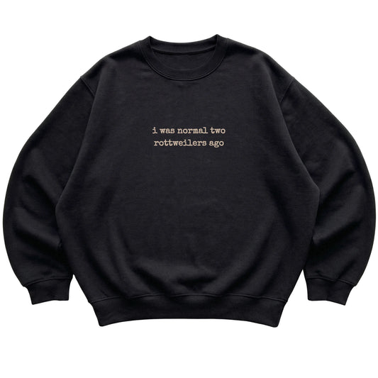 Black I Was Normal Two Rottweilers Ago sweatshirt laid flat