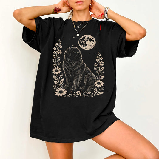 Model wearing a Black Comfort Colors® T-shirt featuring Newfie framed by flowers beneath the moon