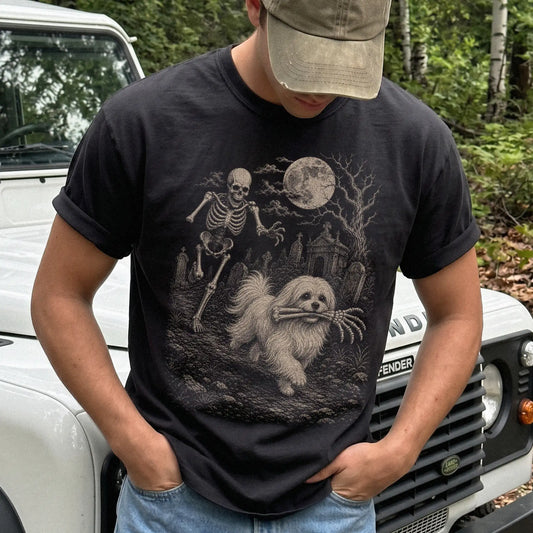 Model wearing a Black Comfort Colors® T-shirt showing Maltese running through a moonlit graveyard with a chasing skeleton