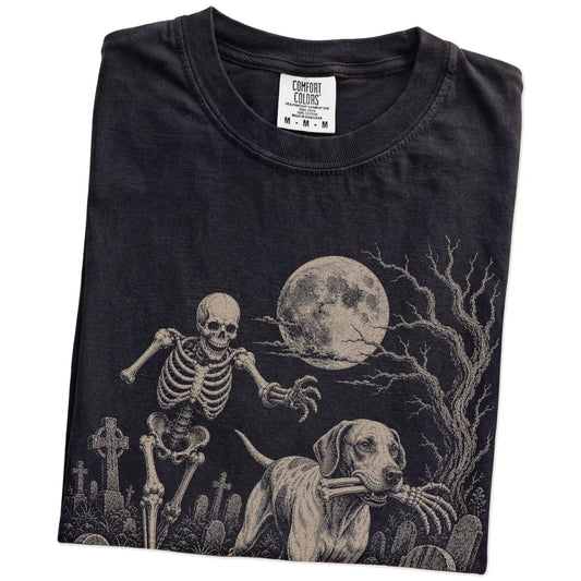 Folded Black Comfort Colors® T-shirt showing Pointer running through a moonlit graveyard with a chasing skeleton