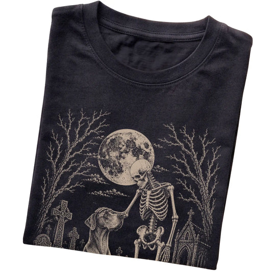 Folded Black T-shirt with a skeleton petting a Great Dane in a graveyard