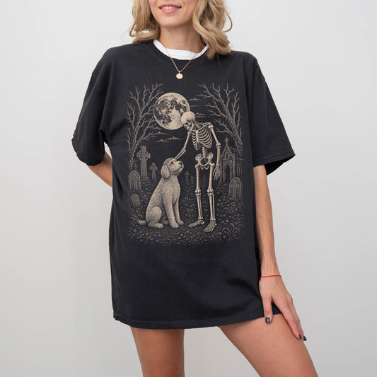 Model wearing a Black Comfort Colors® T-shirt showing Labradoodle sharing a quiet cemetery moment with a friendly skeleton