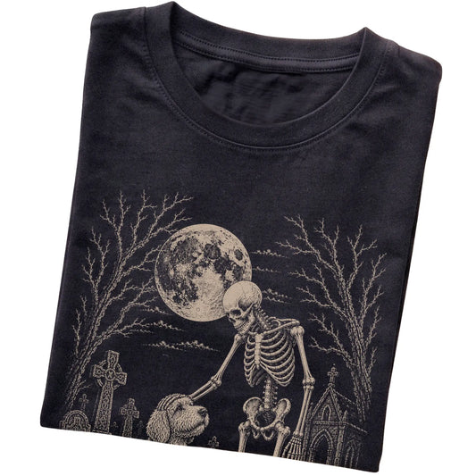 Folded Black T-shirt with a skeleton petting a Labradoodle in a graveyard