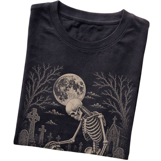 Folded Black T-shirt with a skeleton petting a Schnauzer in a graveyard