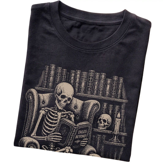Folded Black T-shirt with a skeleton reading Tales Beyond to a Cocker Spaniel