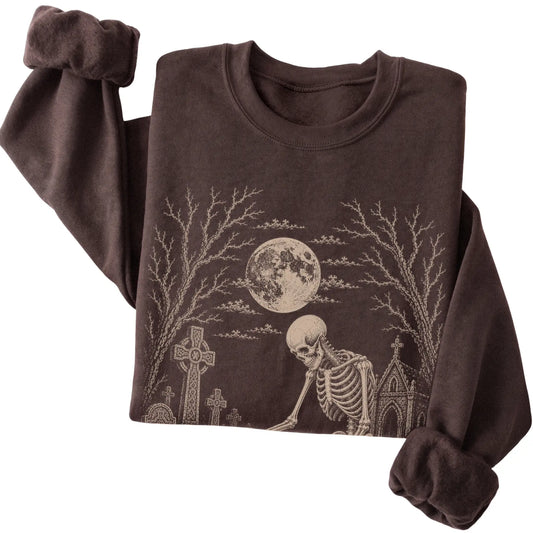 Folded Dark Chocolate sweatshirt with a skeleton petting a Basset Hound in a graveyard