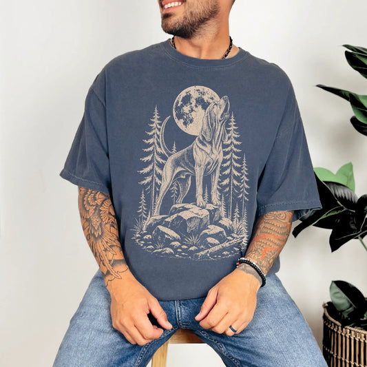 Model wearing a Denim Comfort Colors® T-shirt with a Bloodhound howling beneath the moon and pine trees