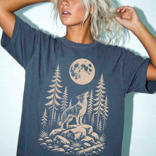 Model wearing a Denim Comfort Colors® T-shirt with a Border Collie howling beneath the moon and pine trees
