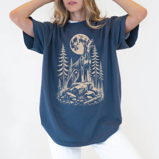 Model wearing a Denim Comfort Colors® T-shirt with a Doberman howling beneath the moon and pine trees