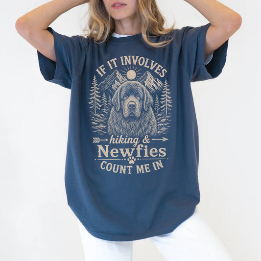 Model wearing a Denim Comfort Colors® T-shirt featuring Newfie hiking design with mountain scenery