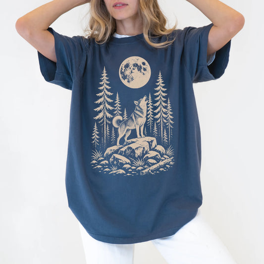 Model wearing a Denim Comfort Colors® T-shirt with a Husky howling beneath the moon and pine trees