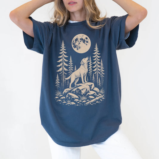 Model wearing a Denim Comfort Colors® T-shirt with a Labrador Retriever howling beneath the moon and pine trees