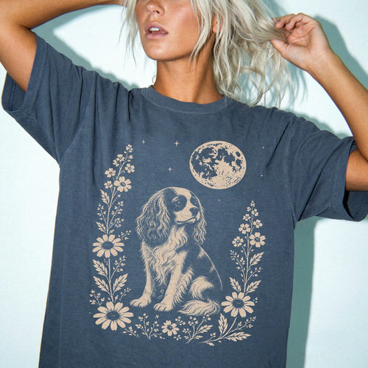 Model wearing a Denim Comfort Colors® T-shirt featuring Cavalier King Charles Spaniel framed by flowers beneath the moon