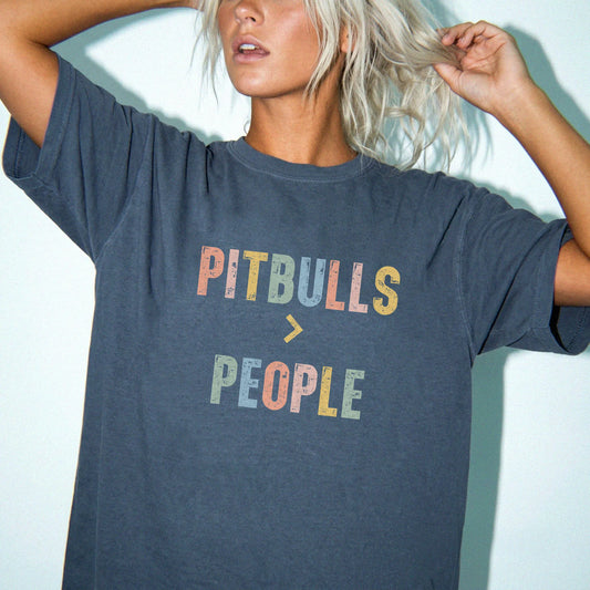 Model wearing a Denim Comfort Colors® T-shirt with “Pitbulls > People” text