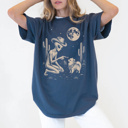 Model wearing a Denim Comfort Colors® T-shirt with cowboy alien fist-bumping a pomeranian beneath the moon