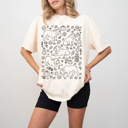 Model wearing a Ivory Comfort Colors® T-shirt with Bulldog dogs with pumpkins, leaves, acorns, and woodland details