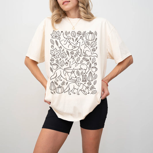 Model wearing a Ivory Comfort Colors® T-shirt with German Shepherd dogs with pumpkins, leaves, acorns, and woodland details