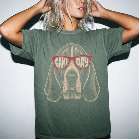 Model wearing a Moss Comfort Colors® T-shirt with basset hound wearing red game day sunglasses