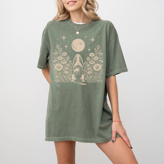 Model wearing a Moss Comfort Colors® T-shirt featuring Basset Hound beneath a wildflower moon
