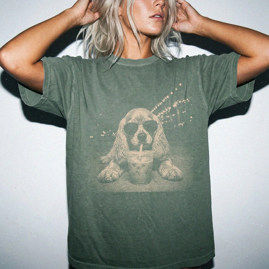 Model wearing a Moss Comfort Colors® T-shirt featuring Cocker Spaniel with iced coffee in a retro grunge design