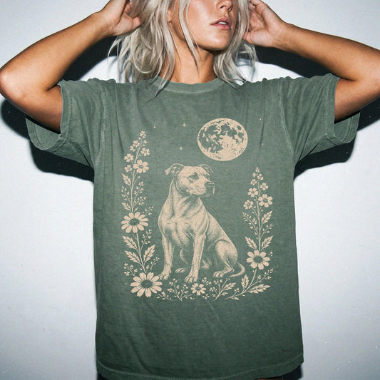 Model wearing a Moss Comfort Colors® T-shirt featuring Pitbull framed by flowers beneath the moon