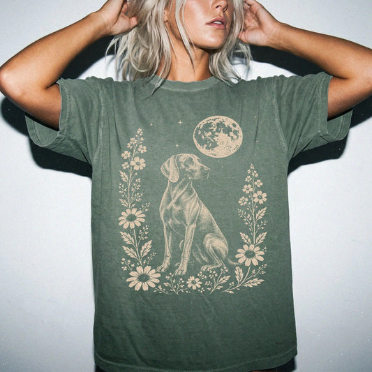 Model wearing a Moss Comfort Colors® T-shirt featuring Weimaraner framed by flowers beneath the moon