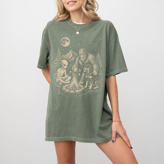 Model wearing a Moss Comfort Colors® T-shirt showing Rottweiler camping with Bigfoot and an alien