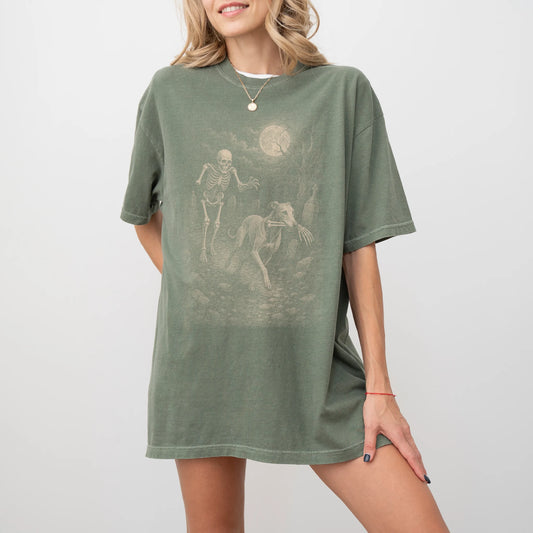Model wearing a Moss Comfort Colors® T-shirt showing Greyhound running through a moonlit graveyard with a chasing skeleton