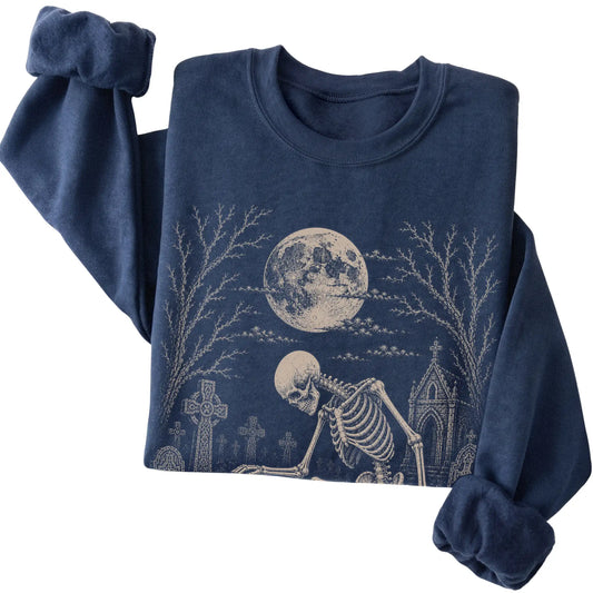 Folded Navy sweatshirt with a skeleton petting a Poodle in a graveyard