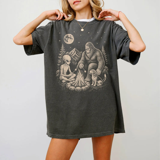 Model wearing a Pepper Comfort Colors® T-shirt showing Beagle camping with Bigfoot and an alien