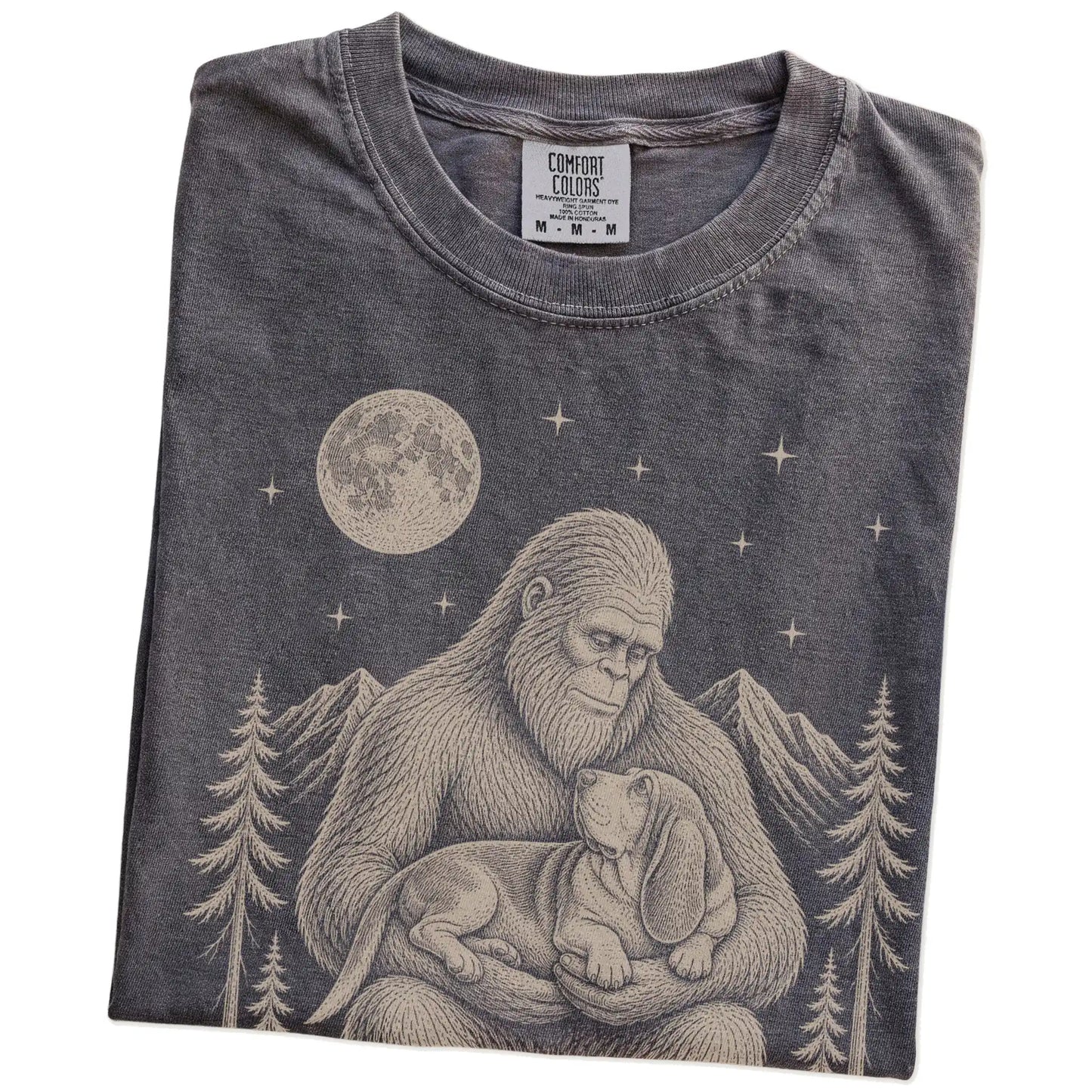 Folded Pepper Comfort Colors® T-shirt showing Bigfoot holding a Basset Hound