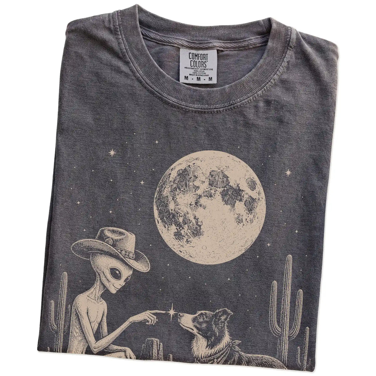 Folded Pepper Comfort Colors® T-shirt showing cowboy alien fist-bumping a border collie beneath the moon