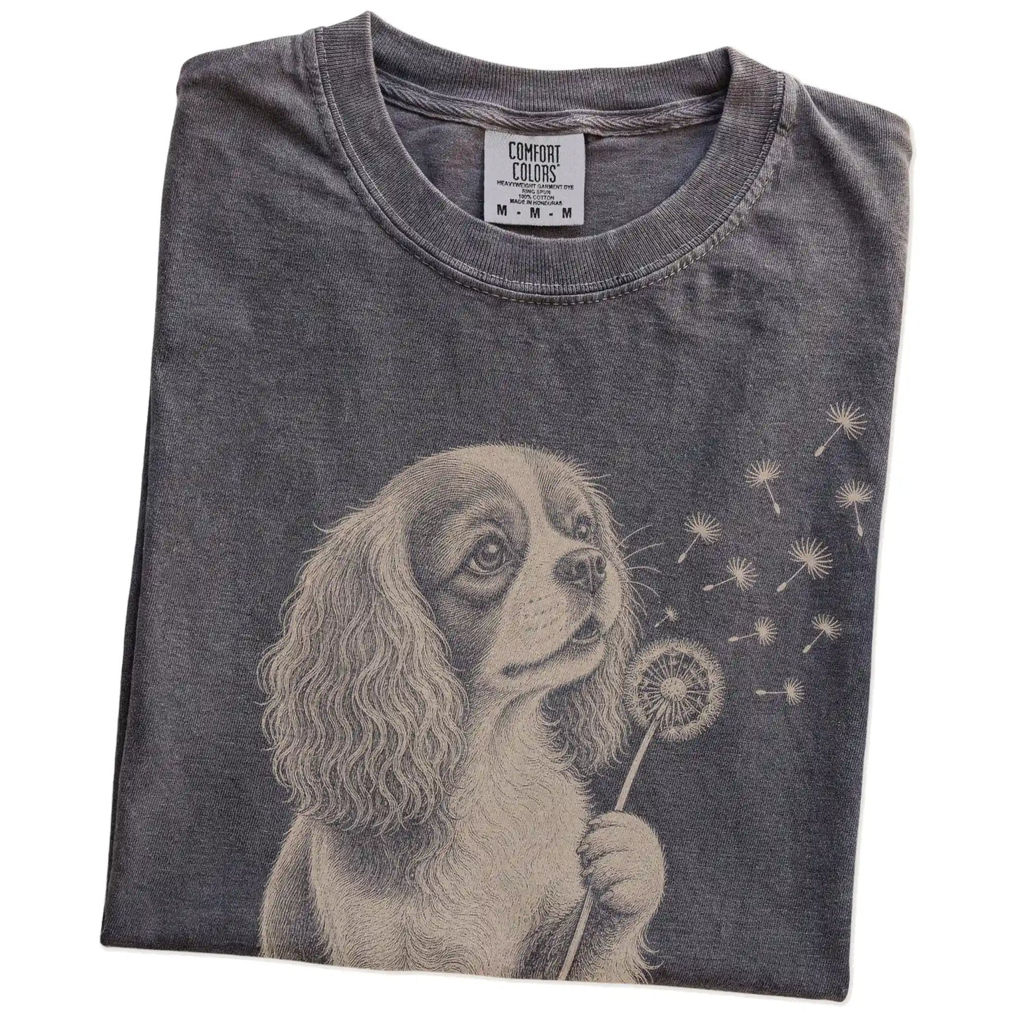 Folded Pepper Comfort Colors® T-shirt showing Cavalier King Charles Spaniel portrait with drifting dandelion seeds
