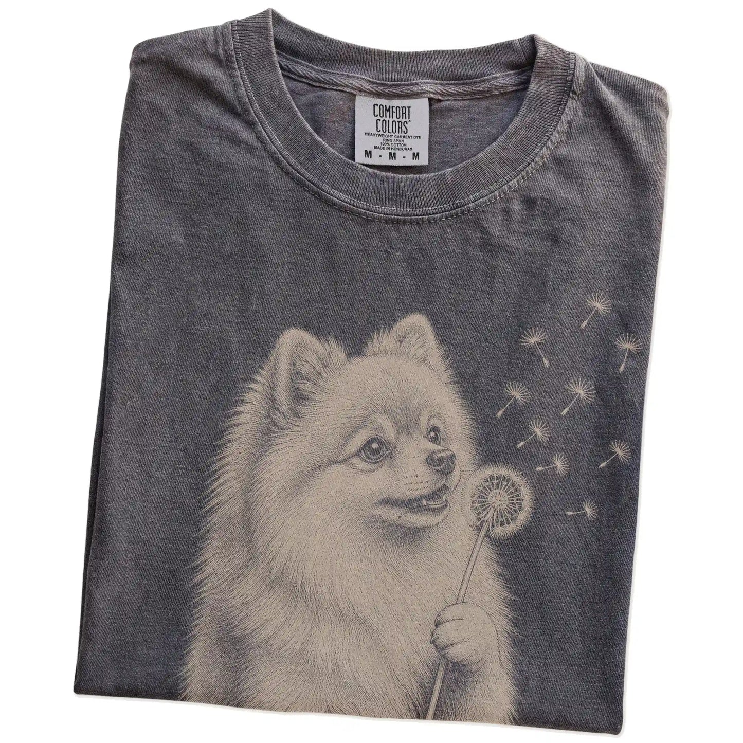 Folded Pepper Comfort Colors® T-shirt showing Pomeranian portrait with drifting dandelion seeds