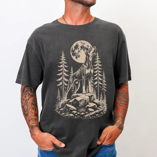 Model wearing a Pepper Comfort Colors® T-shirt with a Doberman howling beneath the moon and pine trees