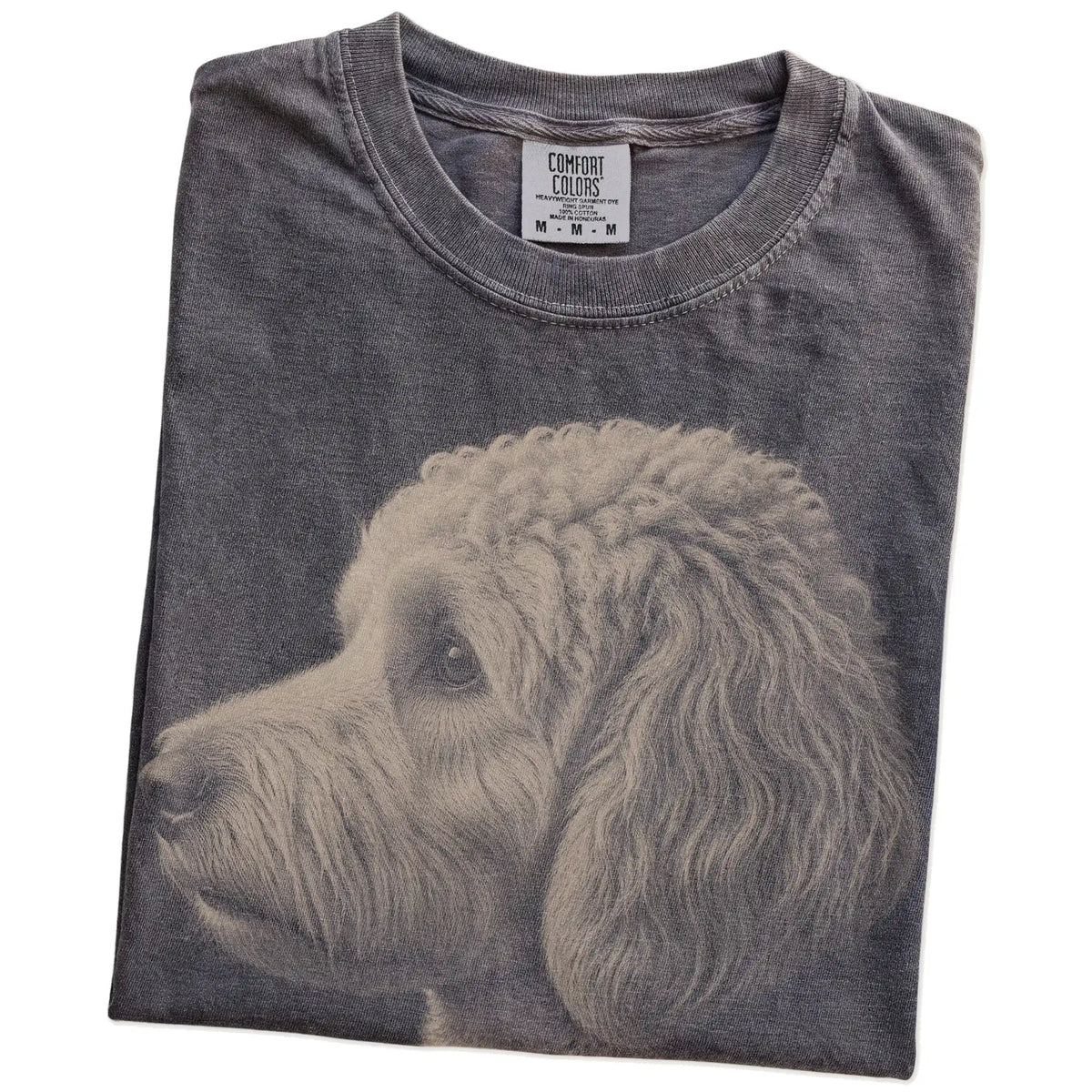 Folded Pepper Comfort Colors® T-shirt showing a detailed photographic portrait of a Goldendoodle