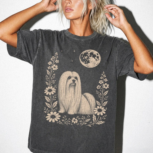 Model wearing a Pepper Comfort Colors® T-shirt featuring Maltese framed by flowers beneath the moon
