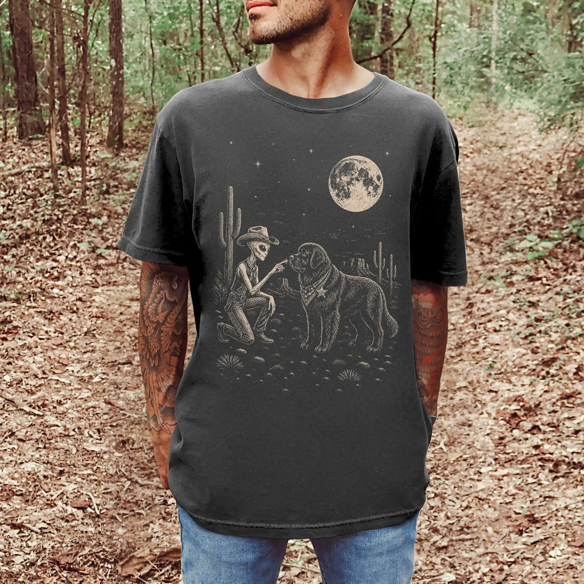 Model wearing a Pepper Comfort Colors® T-shirt with cowboy alien fist-bumping a newfie beneath the moon