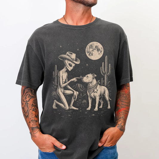 Model wearing a Pepper Comfort Colors® T-shirt with cowboy alien fist-bumping a pitbull beneath the moon