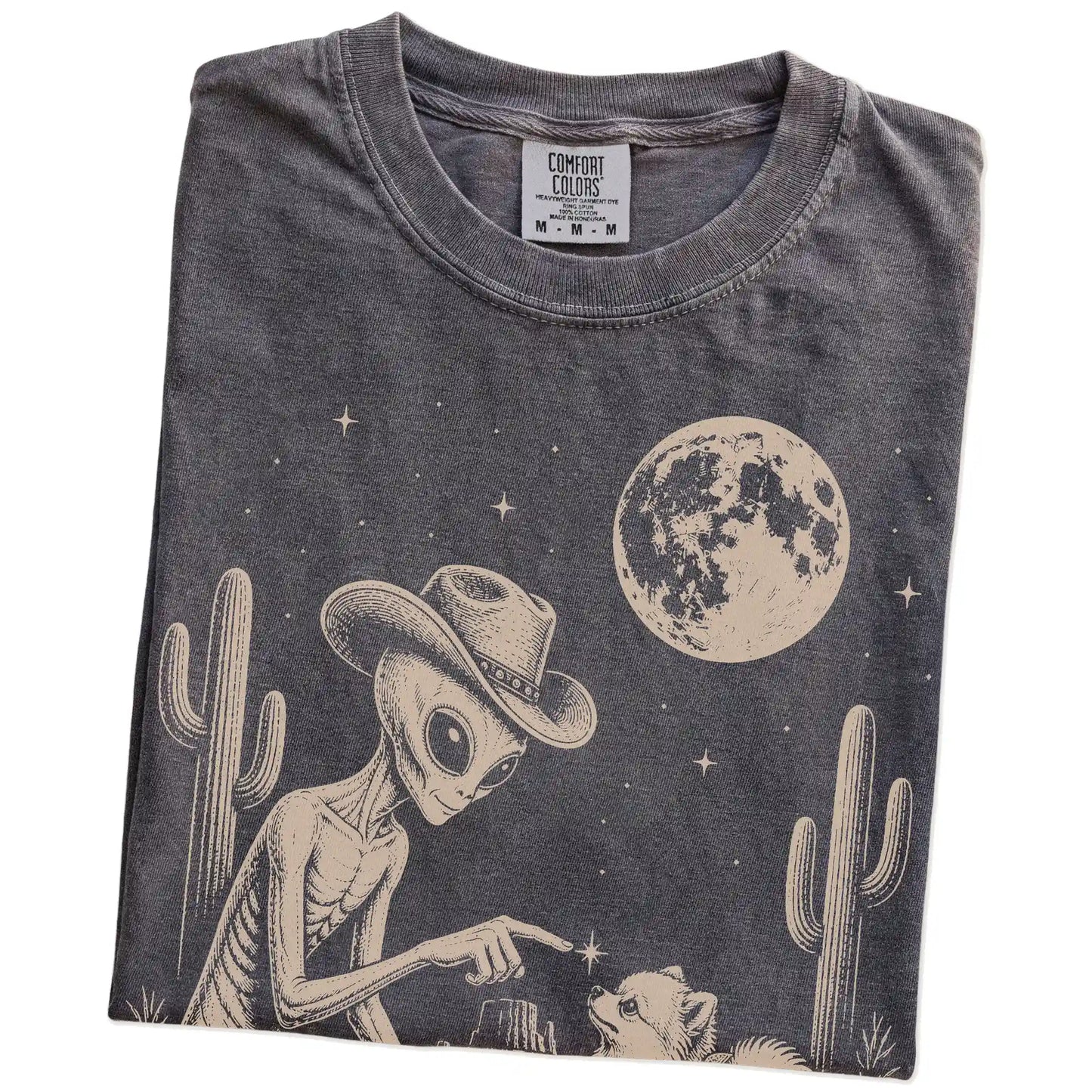 Folded Pepper Comfort Colors® T-shirt showing cowboy alien fist-bumping a pomeranian beneath the moon