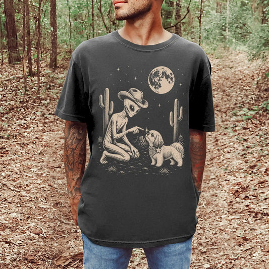 Model wearing a Pepper Comfort Colors® T-shirt with cowboy alien fist-bumping a shih tzu beneath the moon