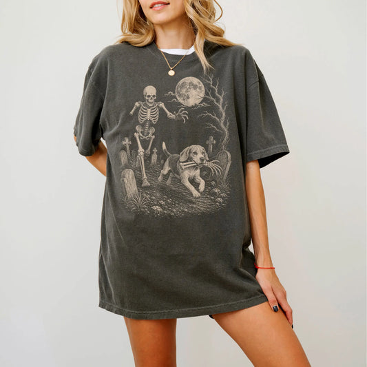 Model wearing a Pepper Comfort Colors® T-shirt showing Beagle running through a moonlit graveyard with a chasing skeleton