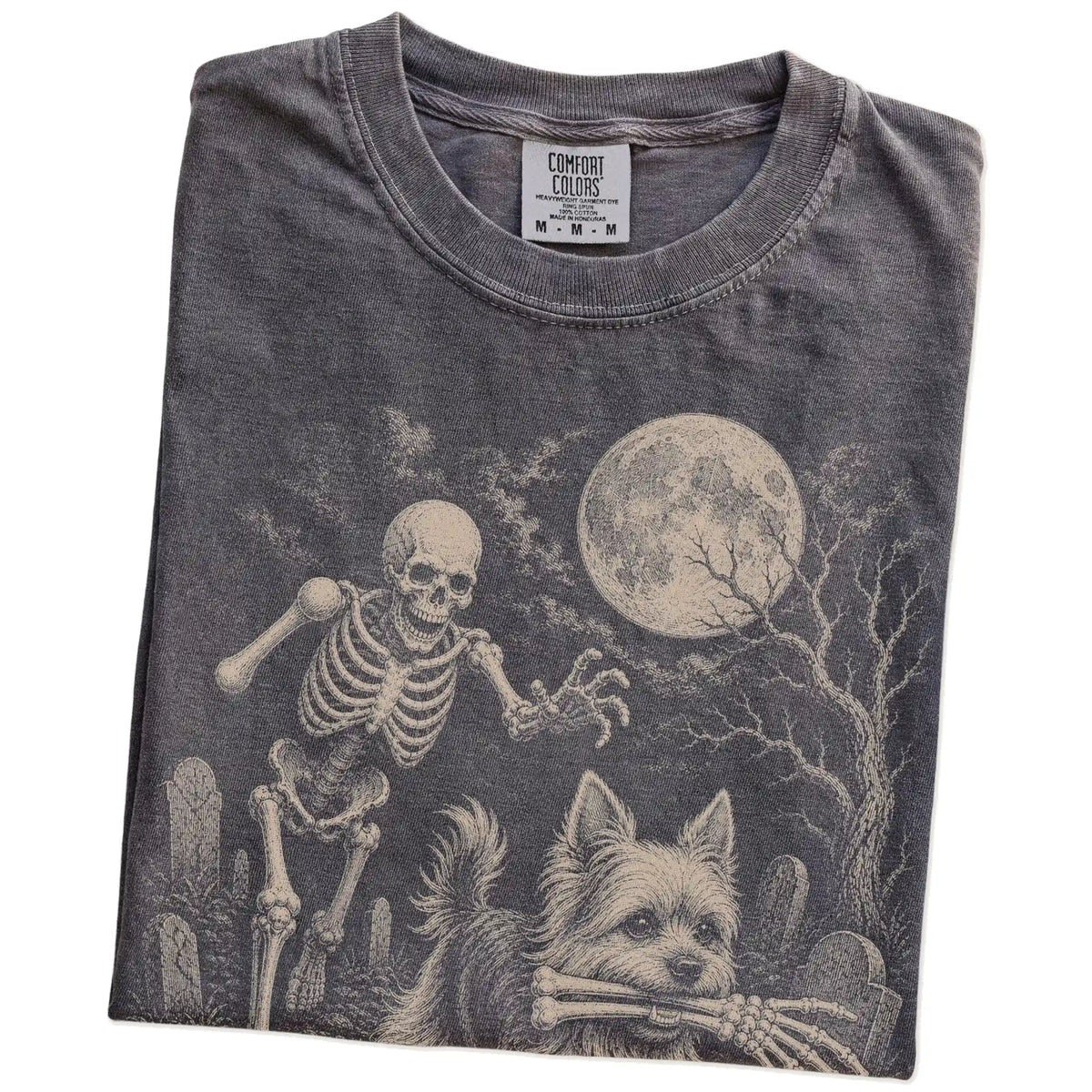Folded Pepper Comfort Colors® T-shirt showing Yorkie running through a moonlit graveyard with a chasing skeleton